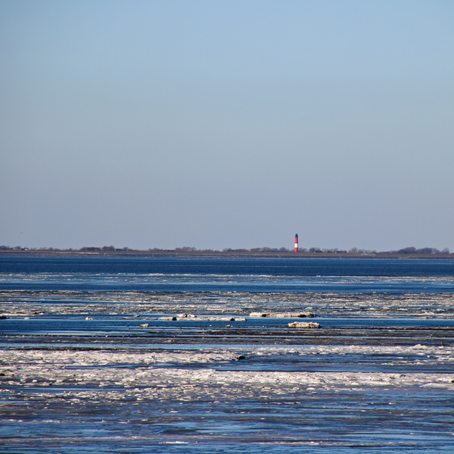Wasser der Nordsee, ein Leuchtturm im Hintergrund
